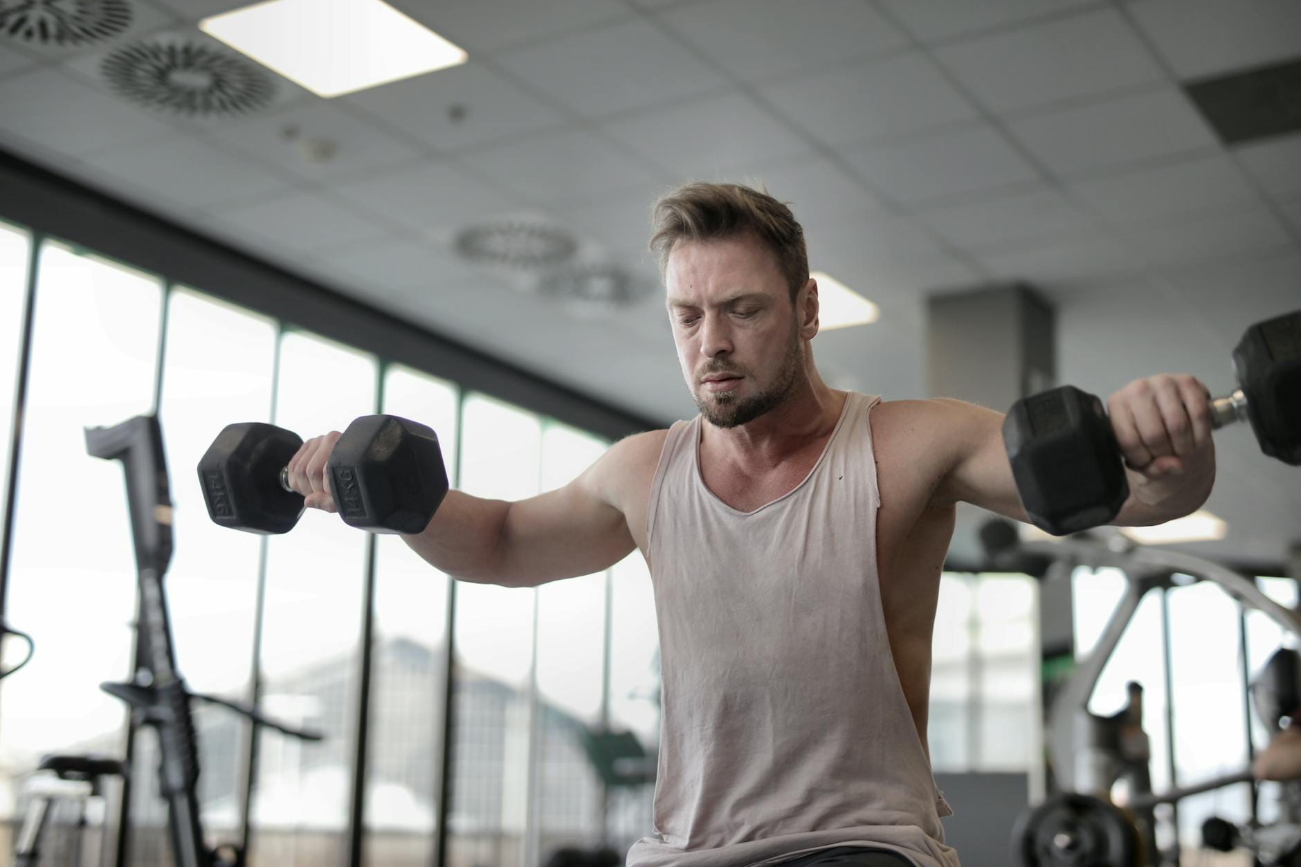 Focused man working out with dumbbells at gym showcasing strength and determination
